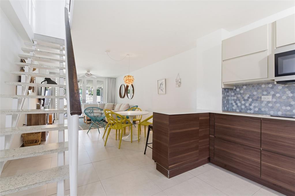 A modern kitchen with wood cabinets and a tile backsplash overlooks a dining and living area — Villas de Playa II DORADO DEL MAR UNIT BB-2, DORADO, PR