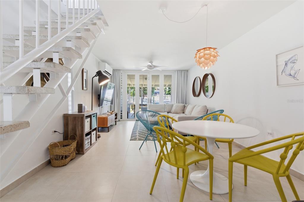 A bright living and dining area features a white staircase, tile floors, and yellow chairs — Villas de Playa II DORADO DEL MAR UNIT BB-2, DORADO, PR