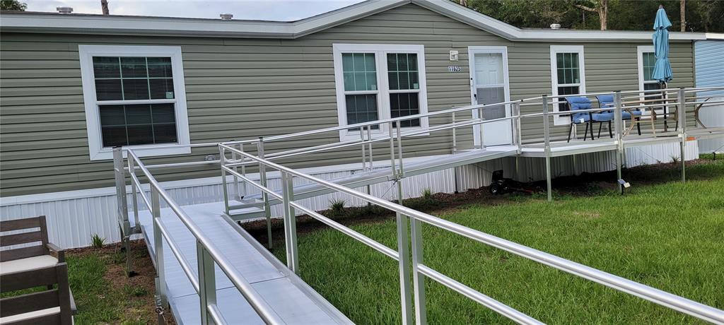 A manufactured home exterior features a large aluminum wheelchair ramp leading to the front door — 11625 NW 20TH STREET, OCALA, FL
