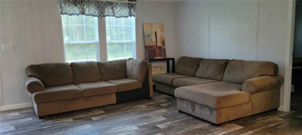 A living room features two brown sofas, wood-look flooring, and windows with patterned valances — 11625 NW 20TH STREET, OCALA, FL