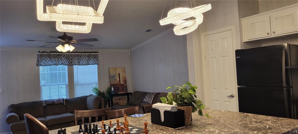 A kitchen island with a chessboard faces a living area with a sofa and chandeliers — 11625 NW 20TH STREET, OCALA, FL