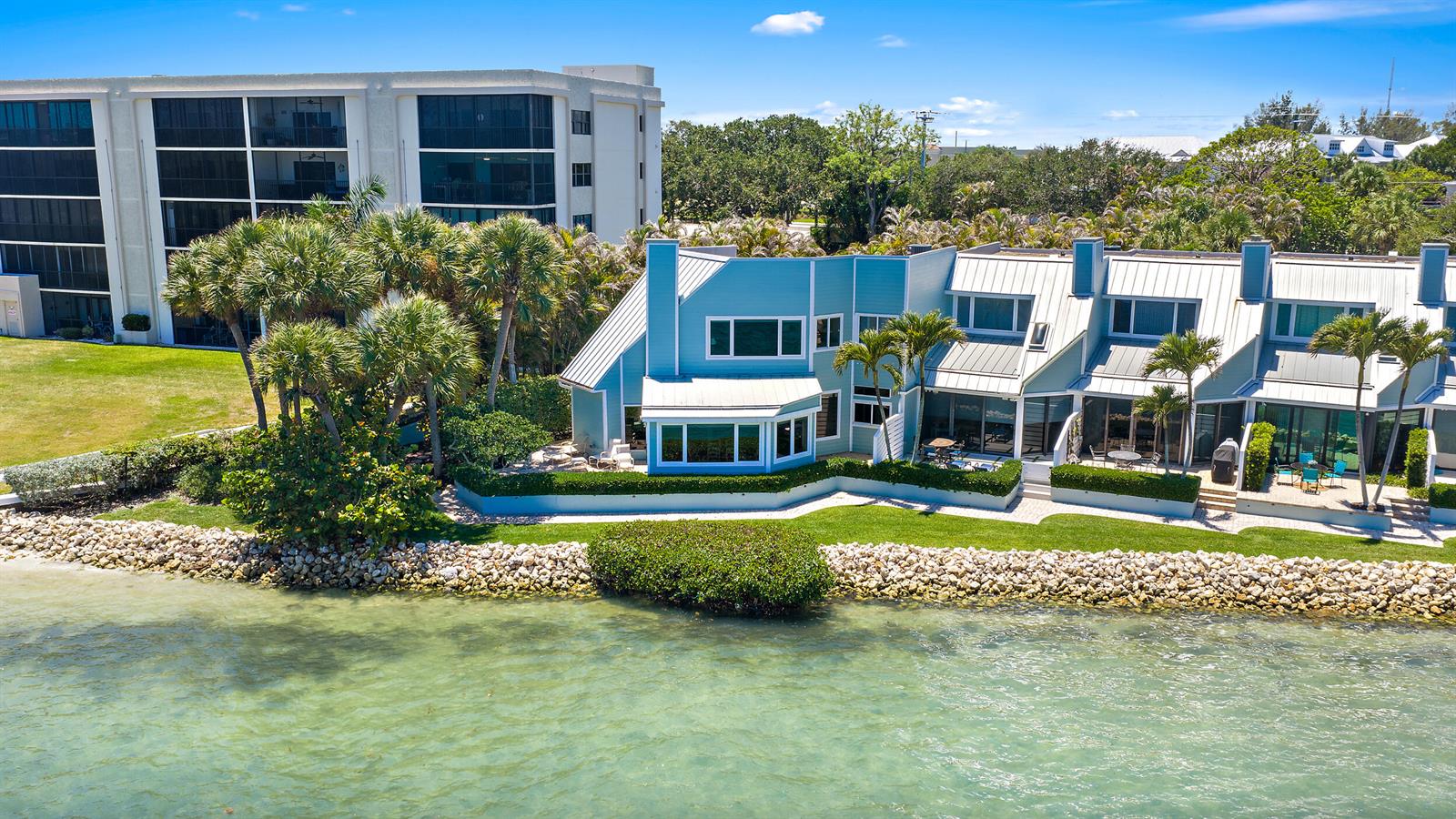 An aerial view of blue waterfront townhomes with metal roofs and palm trees — 19932 Scrimshaw Way, Jupiter FL 33469, JUPITER, FL