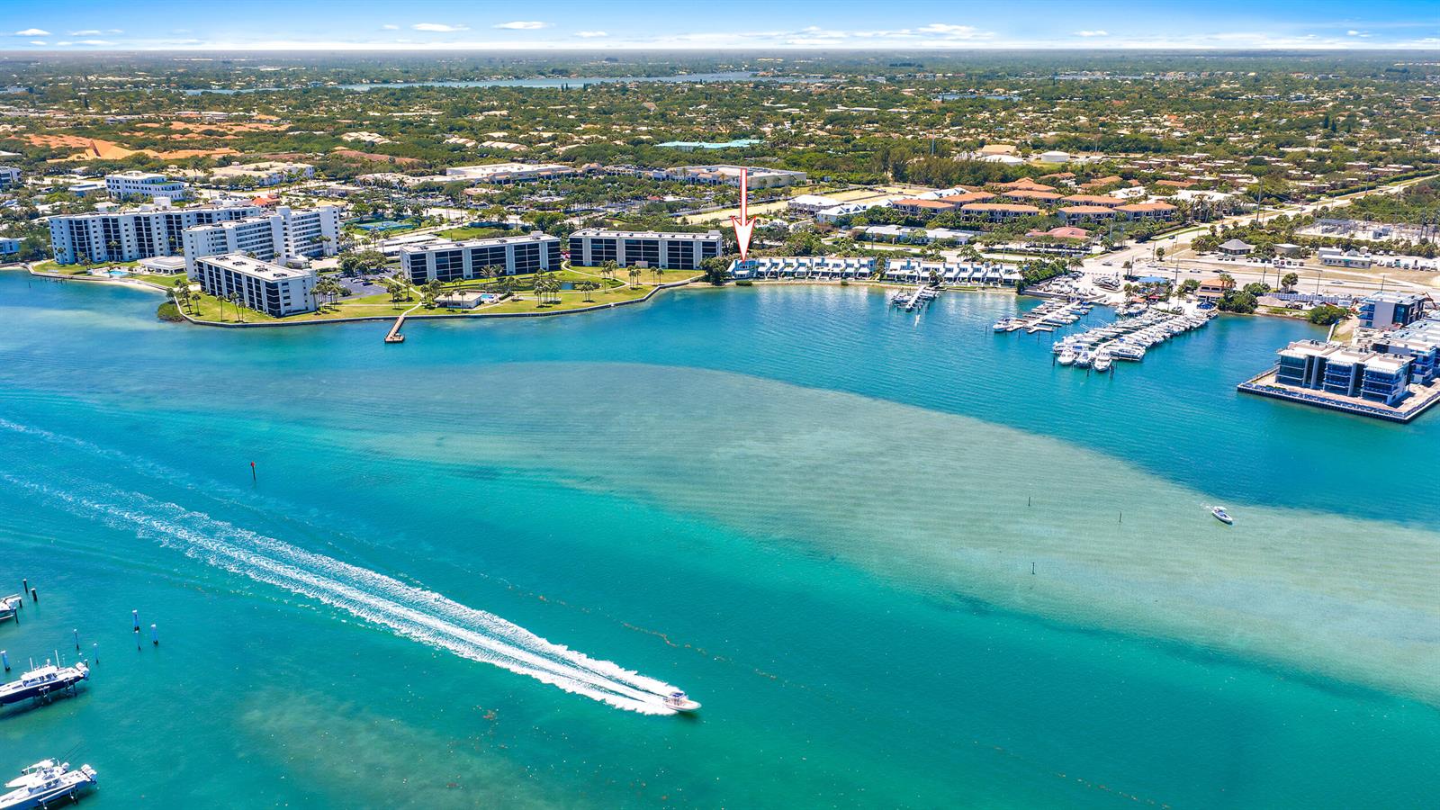 An aerial view shows waterfront residential buildings, a marina, and a boat on the water — 19932 Scrimshaw Way, Jupiter FL 33469, JUPITER, FL