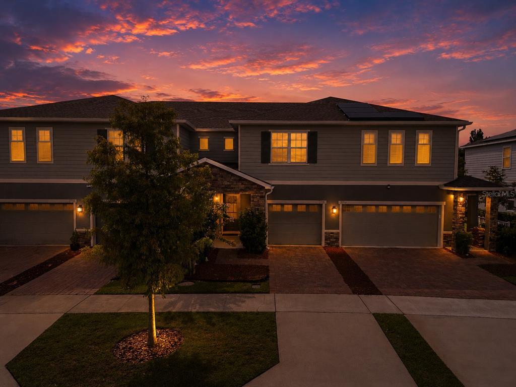 A two-story townhouse exterior with a paved driveway and a sunset sky — 2724 PLEASANT CYPRESS CIRCLE, KISSIMMEE, FL