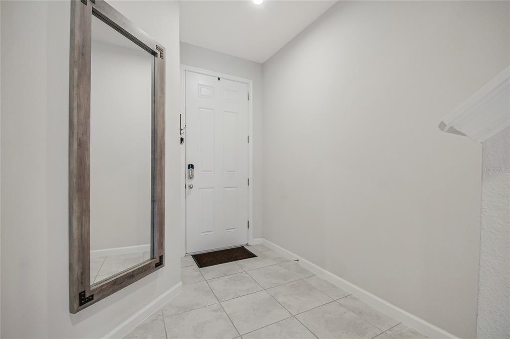 A tiled entryway features a large wall-mounted mirror and a white front door — 2724 PLEASANT CYPRESS CIRCLE, KISSIMMEE, FL