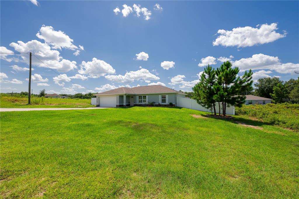 A single-story house with a white garage and a large green lawn under a sky — 263 EMERALD ROAD, OCALA, FL