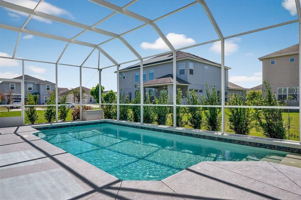 A swimming pool enclosed by a screened lanai with a view of neighboring houses — 6808 FORKMEAD LANE, PORT ORANGE, FL