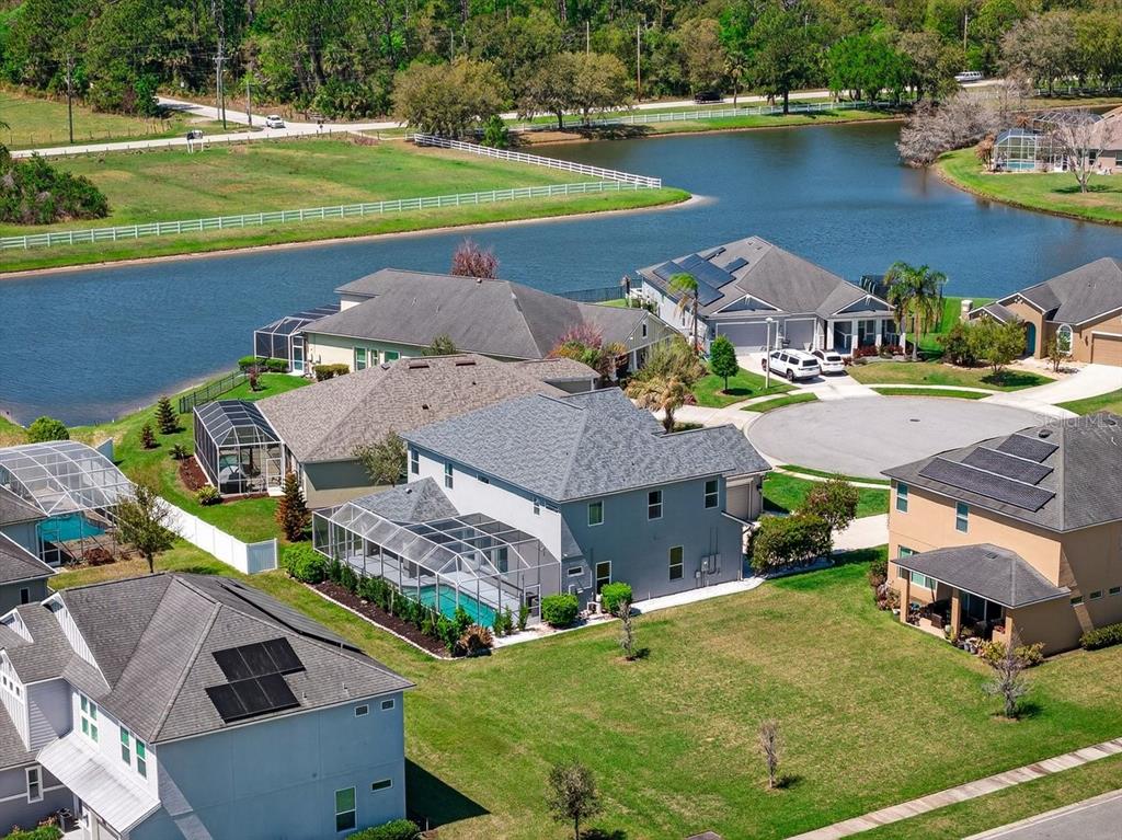 An aerial view of suburban houses with swimming pools and solar panels near a lake — 6808 FORKMEAD LANE, PORT ORANGE, FL