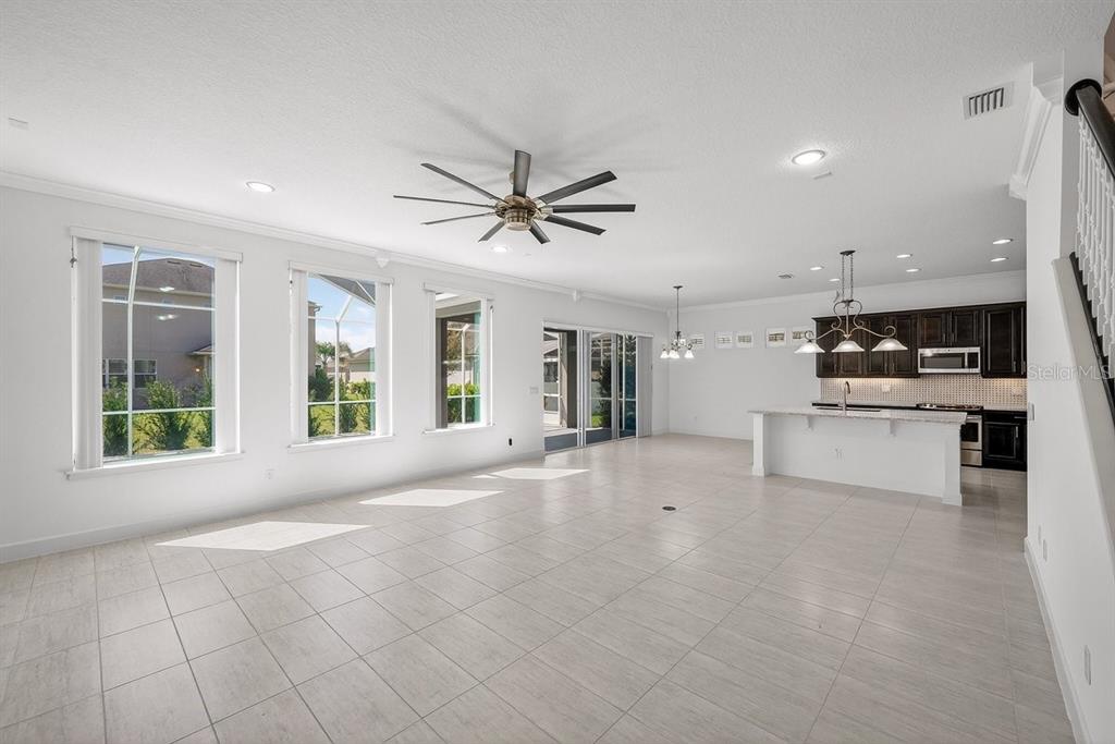 An open-concept living area features white tile floors, a ceiling fan, and a modern kitchen — 6808 FORKMEAD LANE, PORT ORANGE, FL