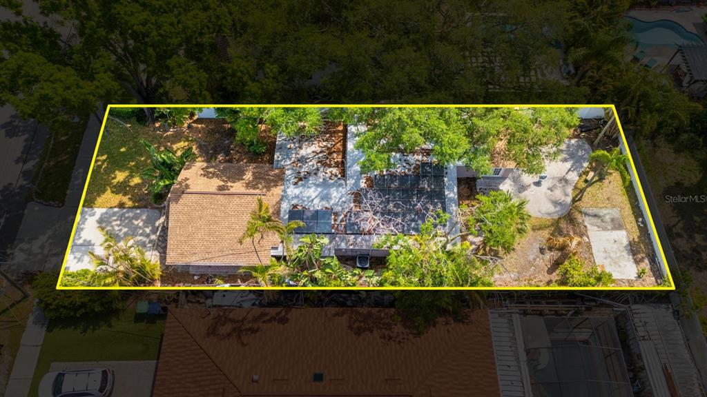 An aerial view shows a house with a shingled roof, solar panels, and surrounding trees — 3414 W WALLCRAFT AVENUE, TAMPA, FL