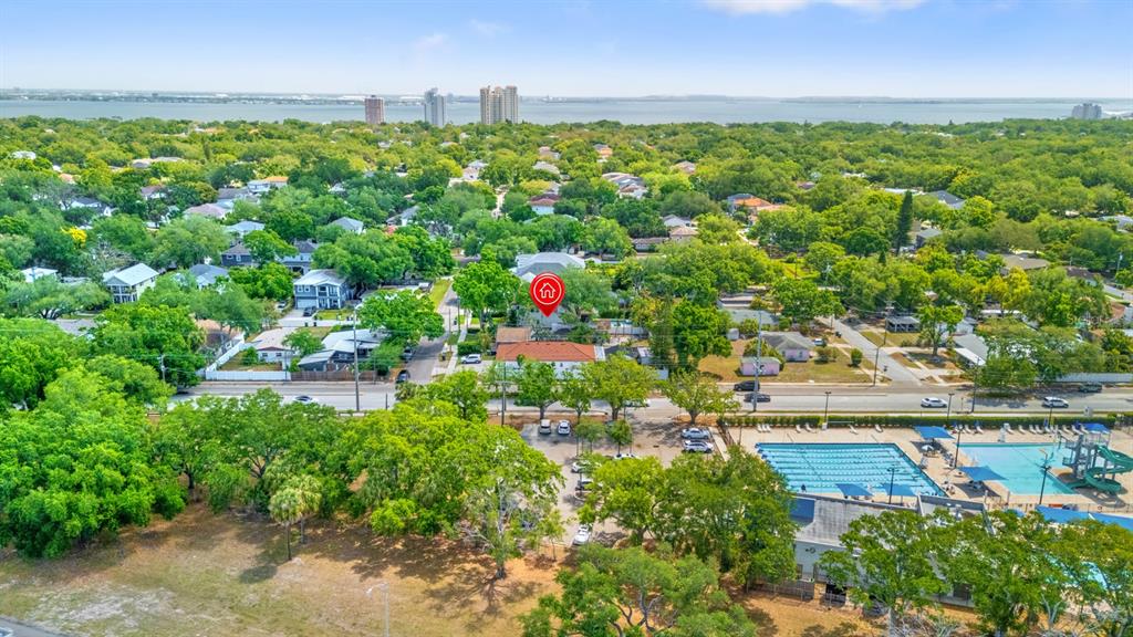 An aerial view shows a residential neighborhood with a swimming pool and nearby water — 3414 W WALLCRAFT AVENUE, TAMPA, FL