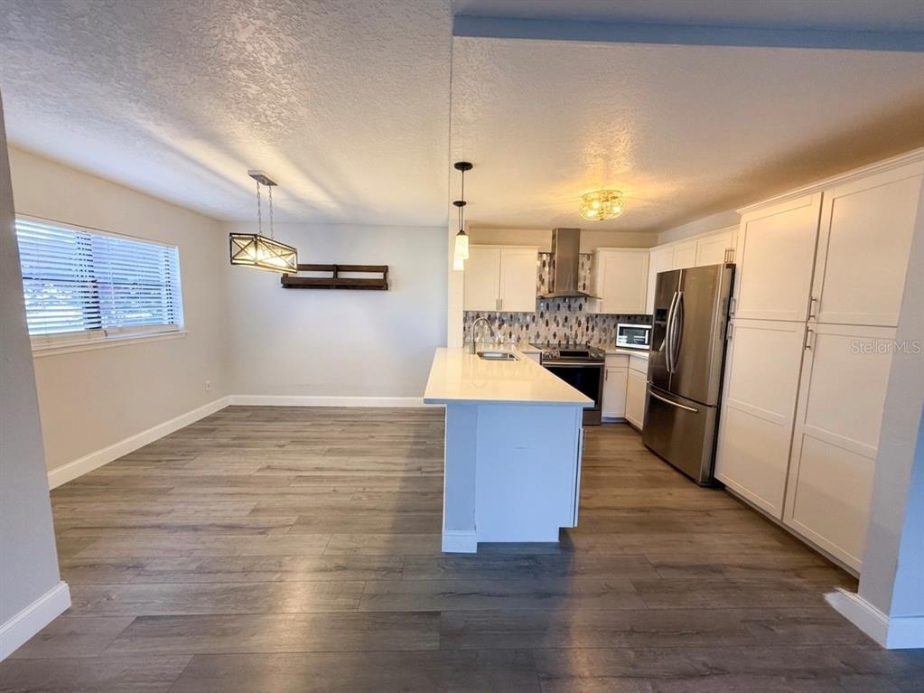 A kitchen and dining area feature white cabinets, stainless steel appliances, and wood-look flooring — 150 KILLARNEY BAY COURT UNIT 5-5, WINTER PARK, FL