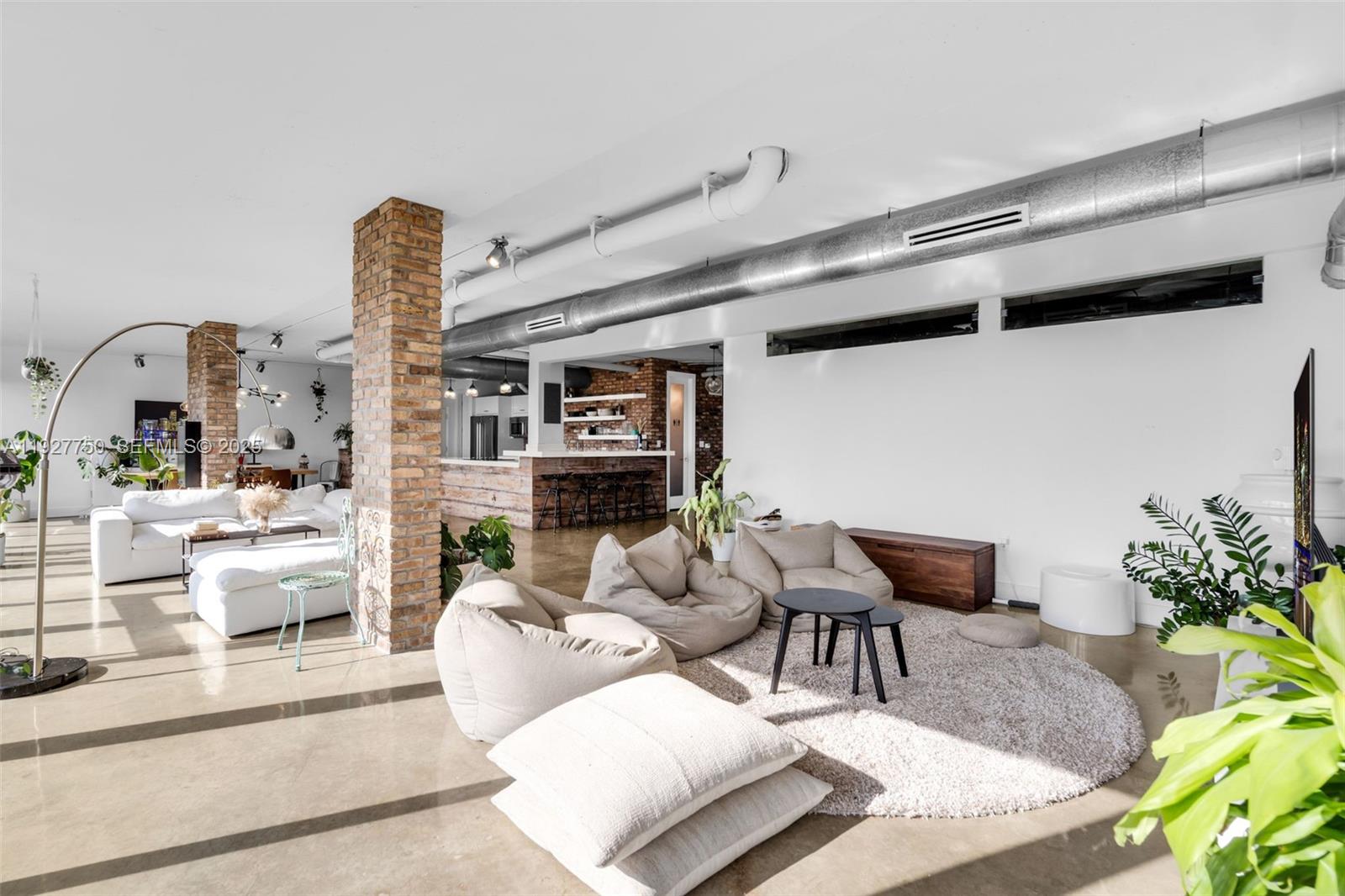 An open-concept living area features polished concrete floors, exposed brick columns, and industrial ductwork — 5701 Biscayne Blvd # 9, Miami FL 33137, MIAMI, FL