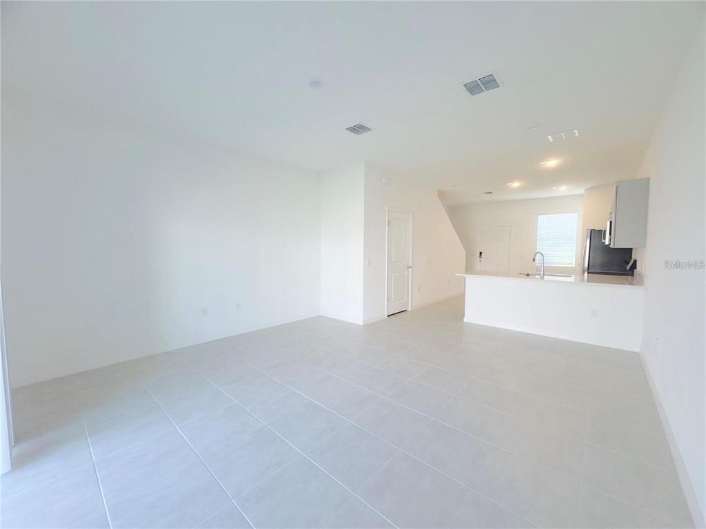 An open-concept living area features light-colored tile flooring, white walls, and a kitchen island — 2852 SKYLINE LOOP, KISSIMMEE, FL