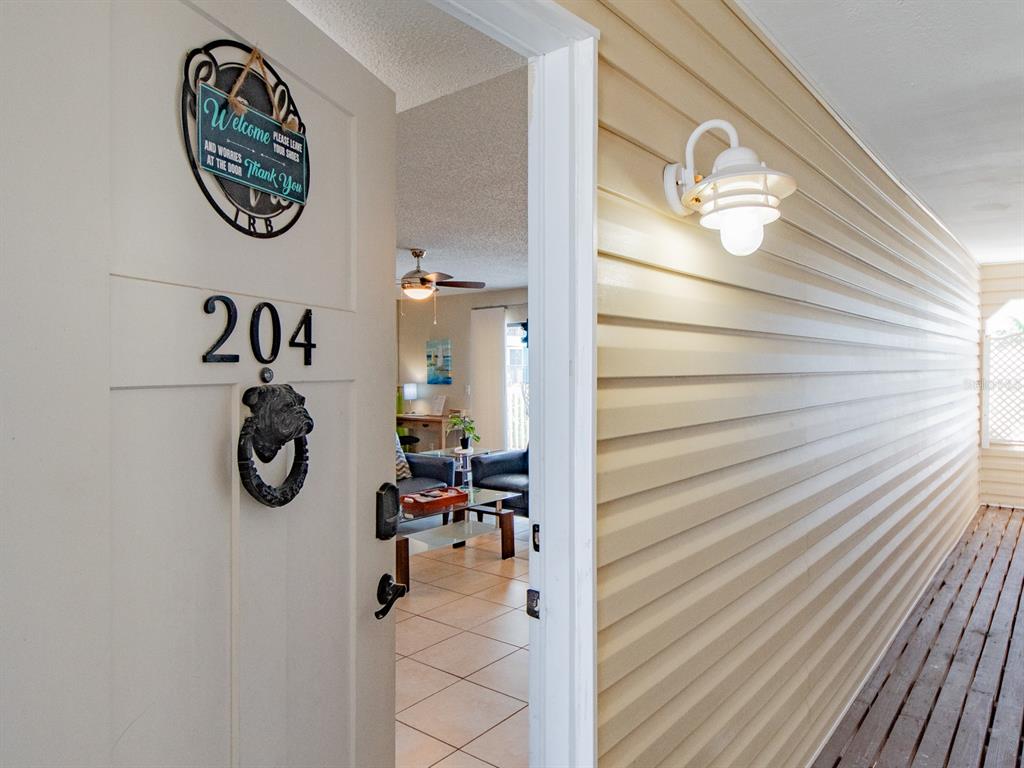 An open door reveals a living room with tile floors and a ceiling fan — 2406 GULF BOULEVARD UNIT 204, INDIAN ROCKS BEACH, FL