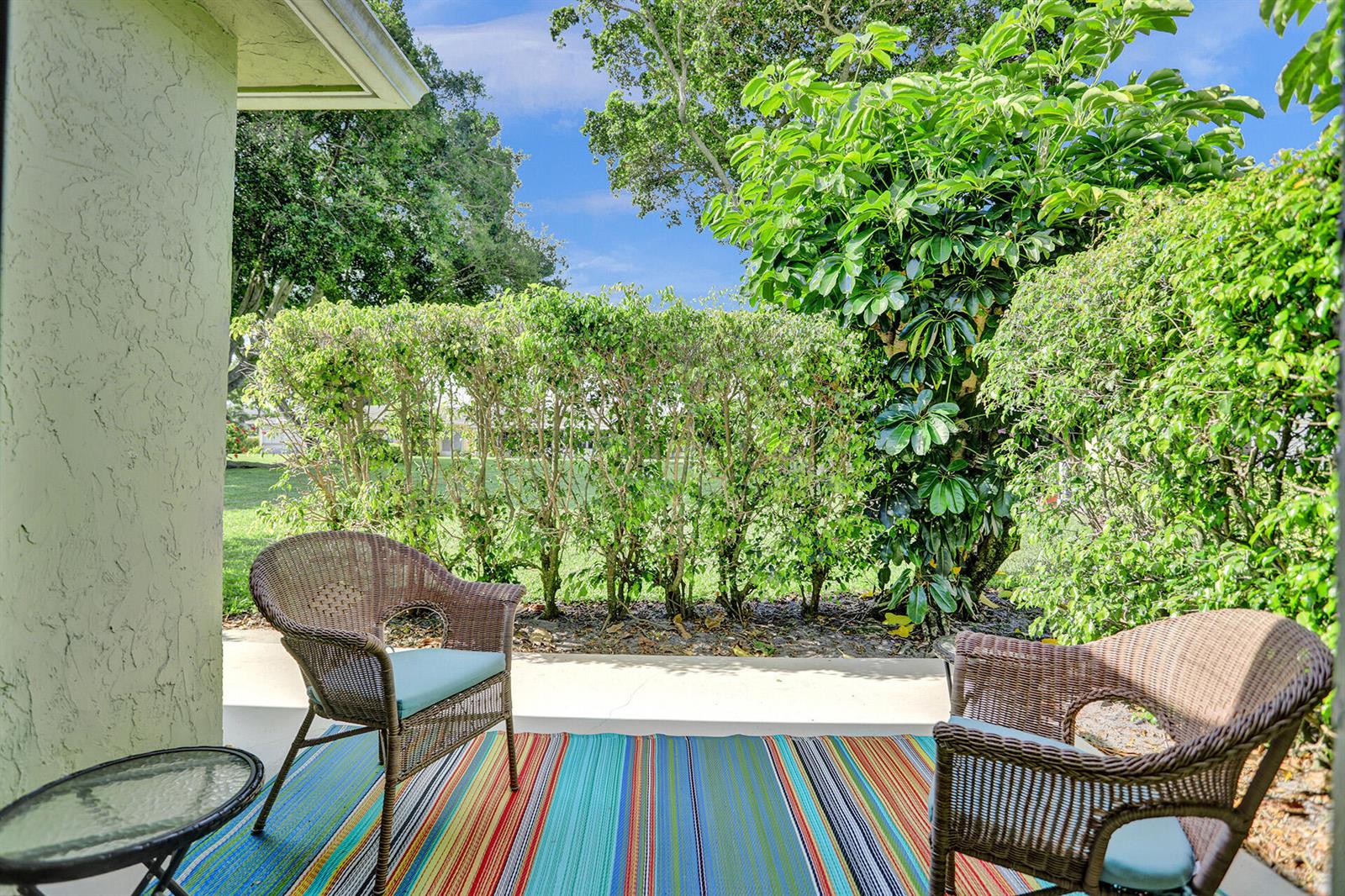 A patio with two wicker chairs, a small table, and a colorful striped rug — 2520 Pansey Lane # D, Delray Beach FL 33445, DELRAY BEACH, FL