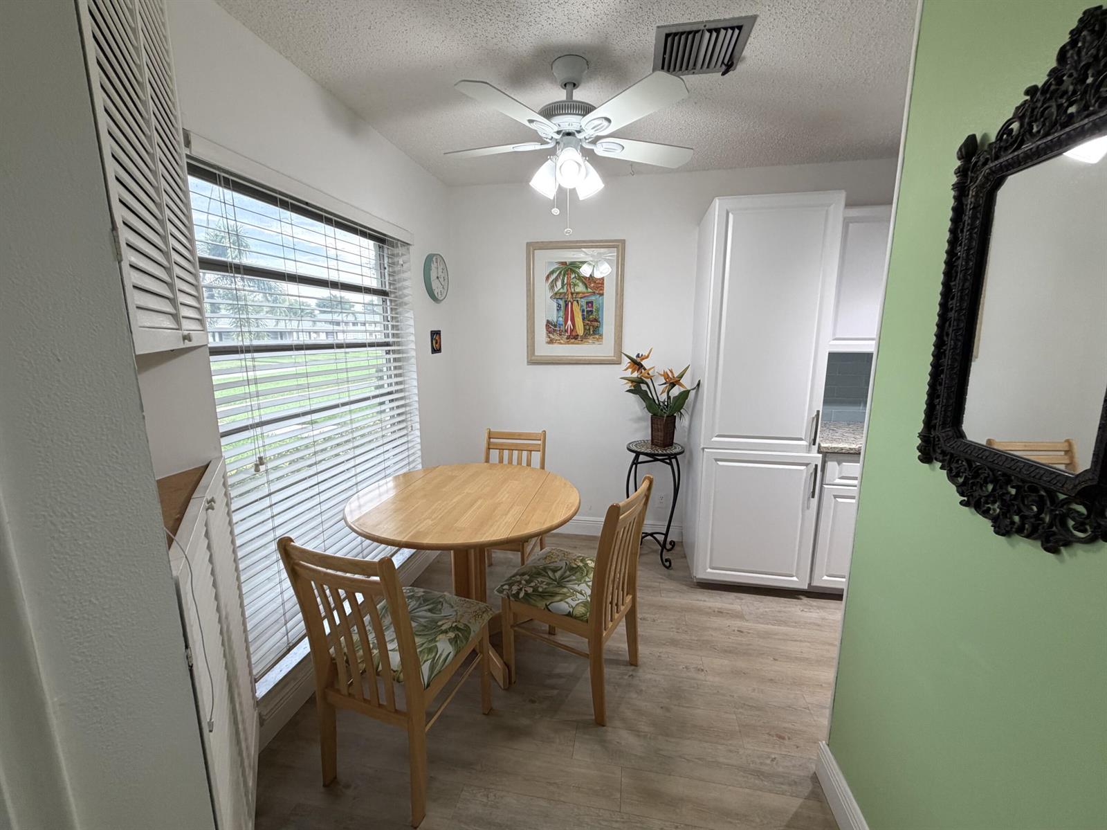 A dining area features a round wooden table, two chairs, and a ceiling fan — 2520 Pansey Lane # D, Delray Beach FL 33445, DELRAY BEACH, FL