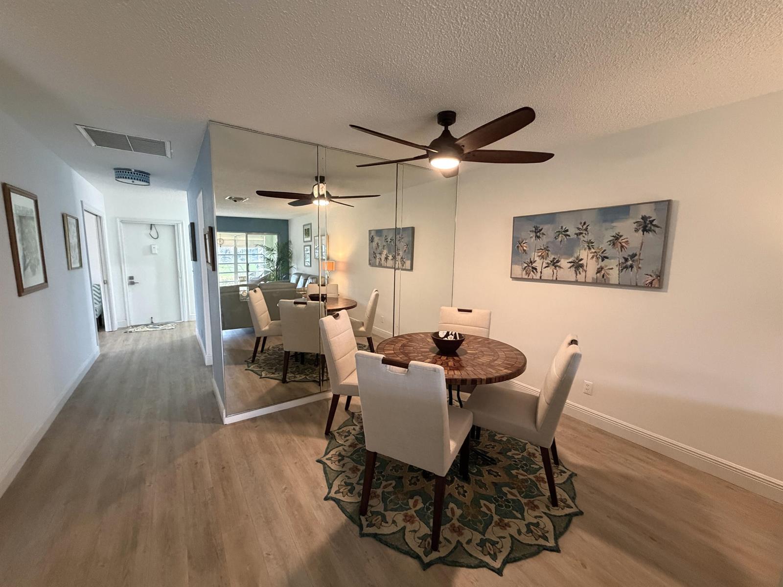 A dining area features a round table, four chairs, a patterned rug, and mirrored walls — 2520 Pansey Lane # D, Delray Beach FL 33445, DELRAY BEACH, FL
