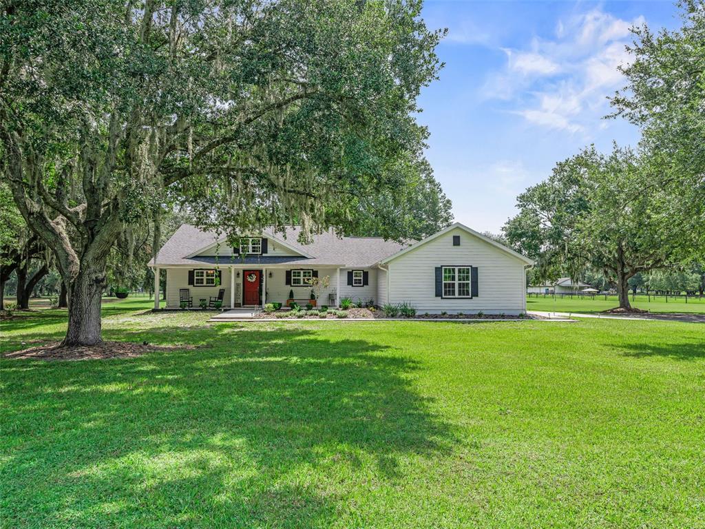 A black metal gate with a letter G monogram stands at the entrance of a driveway — 1539 SE 34TH WAY, SUMTERVILLE, FL