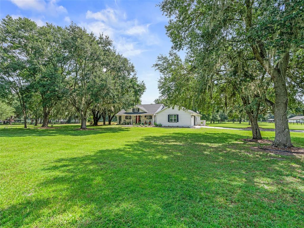 A single-story house with a red front door, covered porch, and light-colored siding — 1539 SE 34TH WAY, SUMTERVILLE, FL