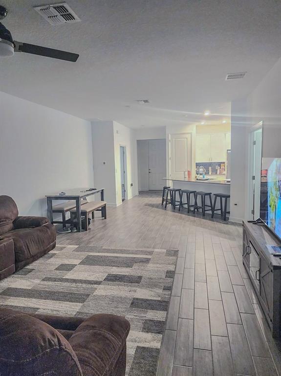 An open-concept living room and kitchen area with gray tile flooring and a dining set — 1743 GOOD NEIGHBOR LOOP, KISSIMMEE, FL