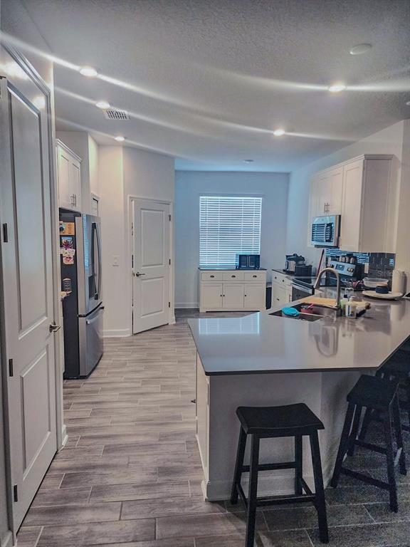 A kitchen with white cabinets, gray countertops, a center island, and wood-look tile flooring — 1743 GOOD NEIGHBOR LOOP, KISSIMMEE, FL