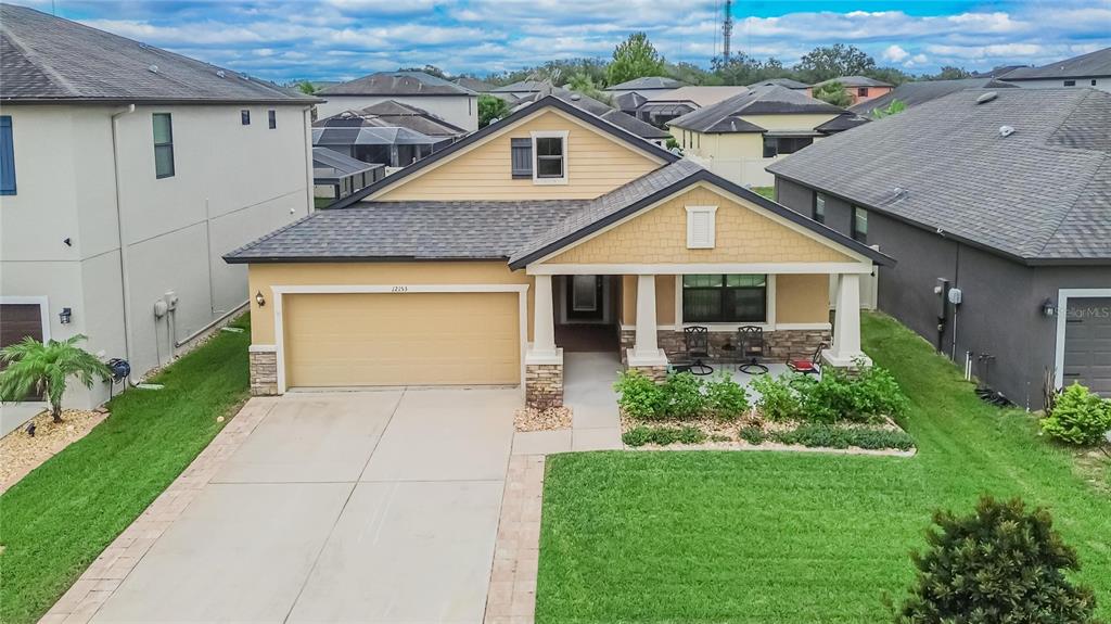 A single-story house with a yellow exterior, stone accents, a two-car garage, and a porch — 12153 CREEK PRESERVE DRIVE, RIVERVIEW, FL