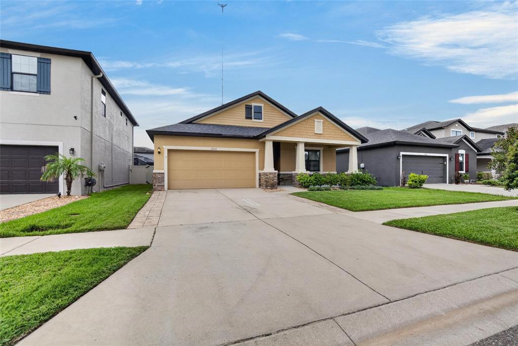 A single-story house with a tan stucco exterior, stone accents, and a two-car garage — 12153 CREEK PRESERVE DRIVE, RIVERVIEW, FL