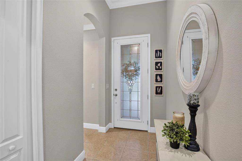 A foyer features a white front door with glass panels, tile flooring, and a round mirror — 12153 CREEK PRESERVE DRIVE, RIVERVIEW, FL