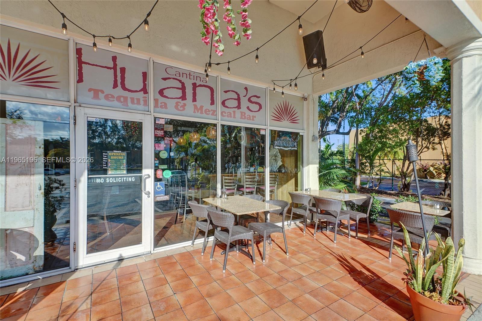 An outdoor patio seating area features tables and chairs in front of a restaurant storefront — 15400 Biscayne Blvd, North Miami FL 33160, NORTH MIAMI, FL