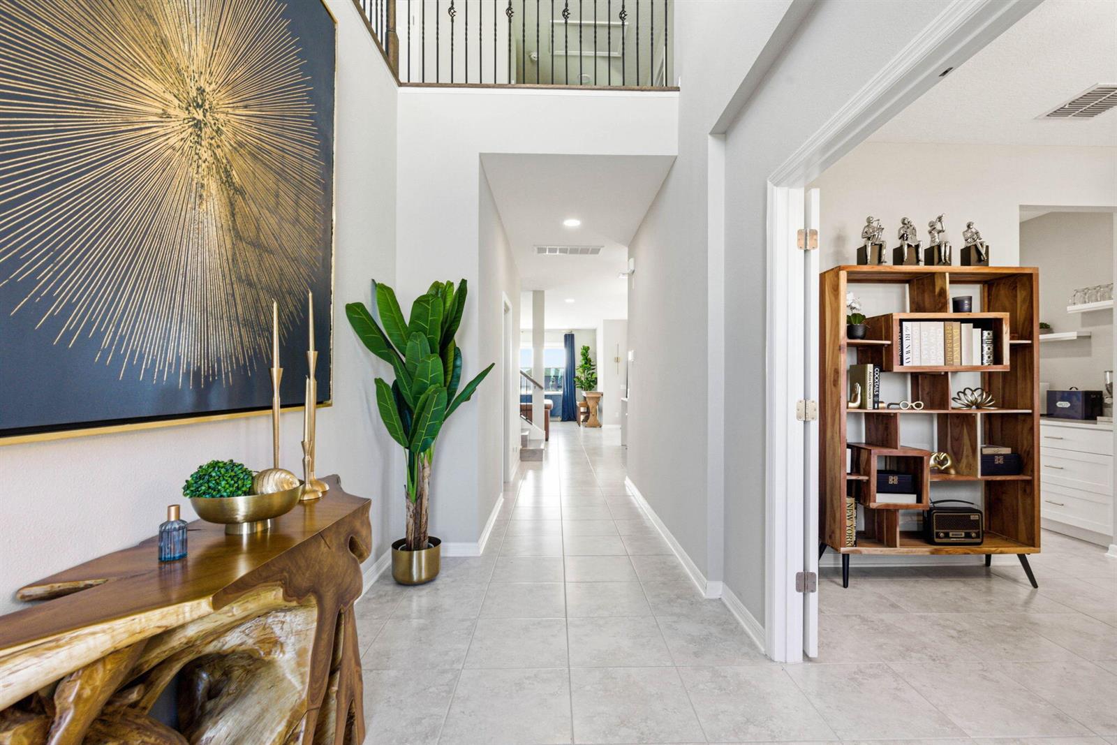 A bright entryway features a live-edge console table, a large abstract painting, and tile flooring — 9522 Seagrass Port Pass, FL 33545, FL