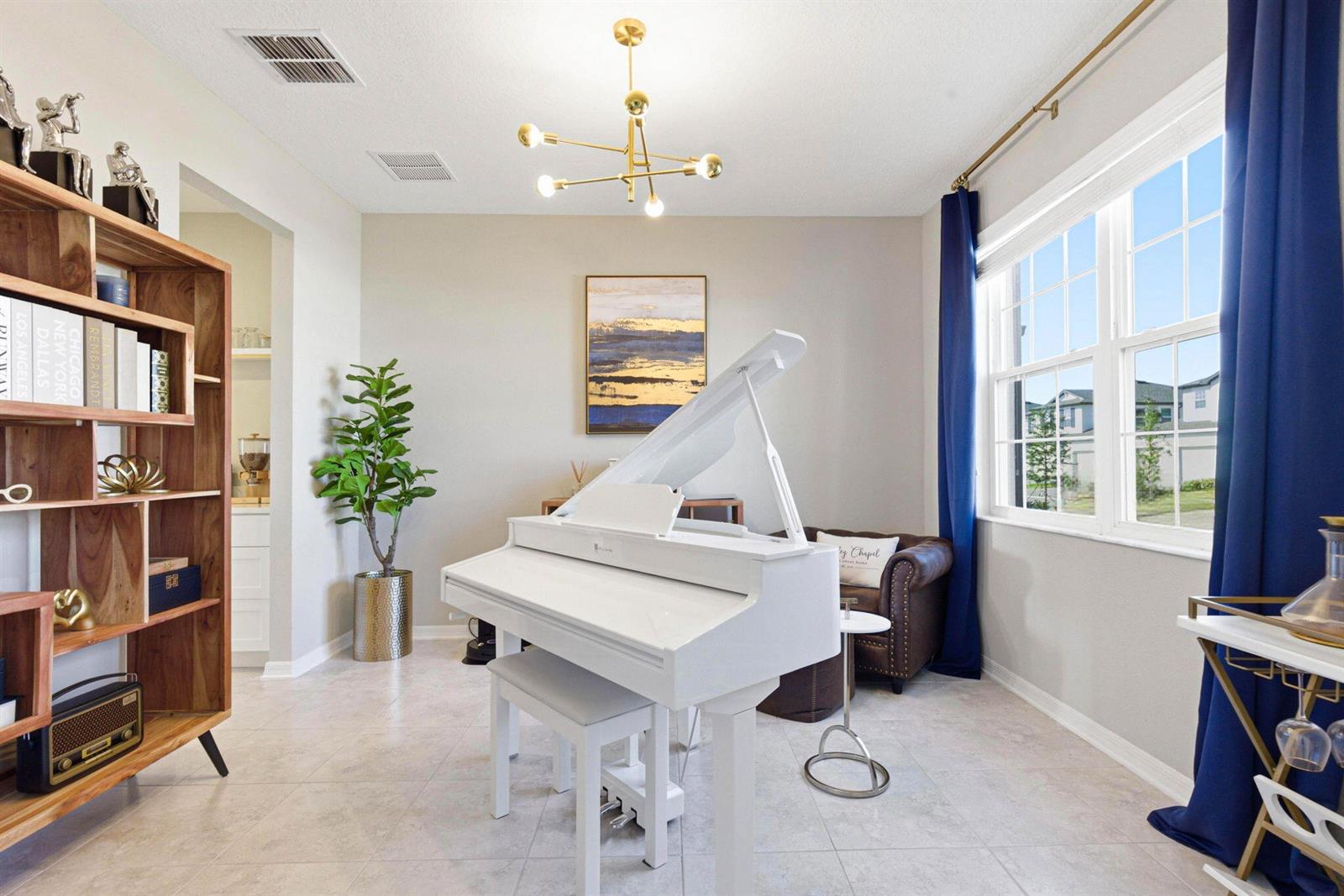 A white grand piano sits in a room with a wooden bookshelf and blue curtains — 9522 Seagrass Port Pass, FL 33545, FL