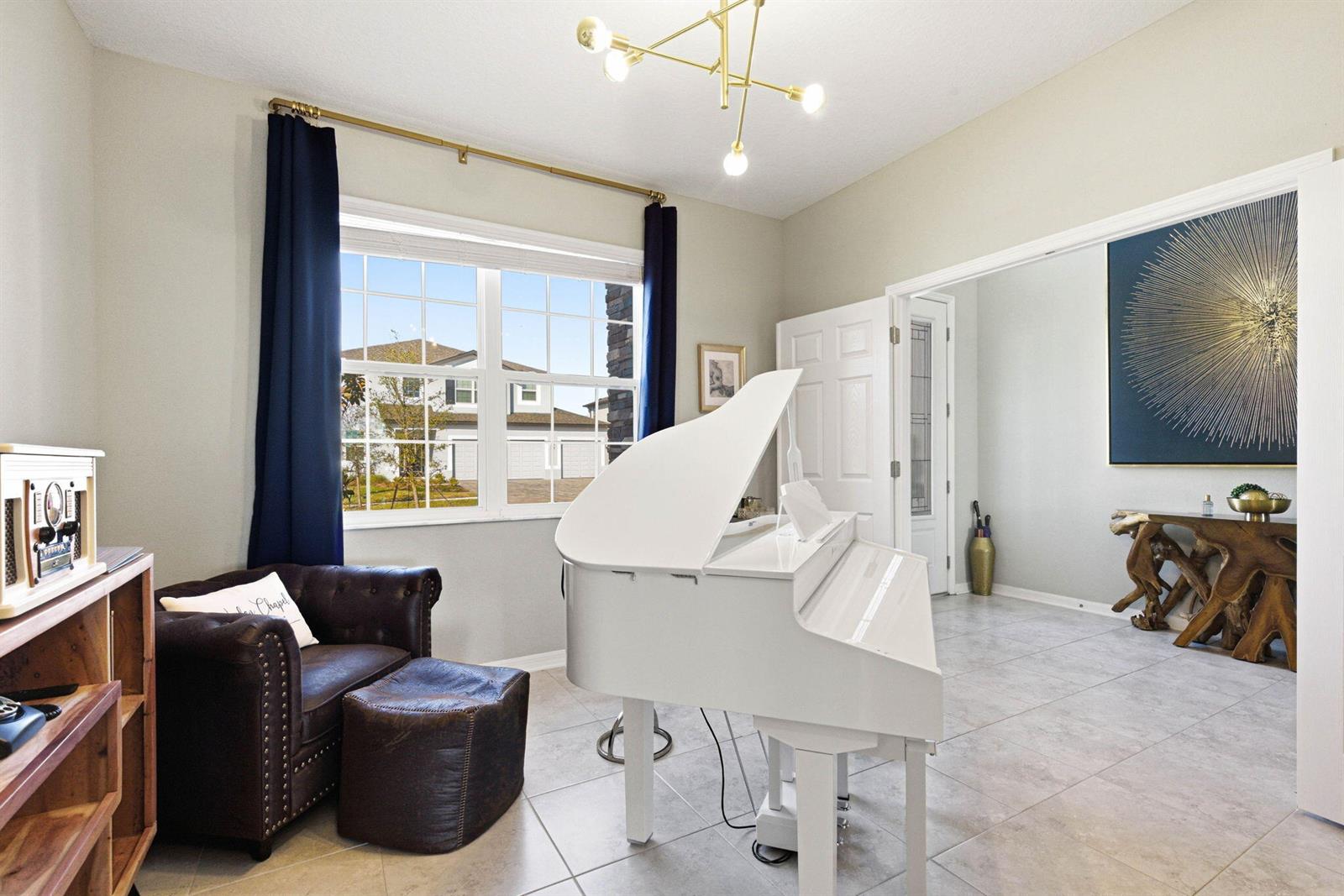 A white grand piano sits in a tiled room with a leather chair and curtains — 9522 Seagrass Port Pass, FL 33545, FL