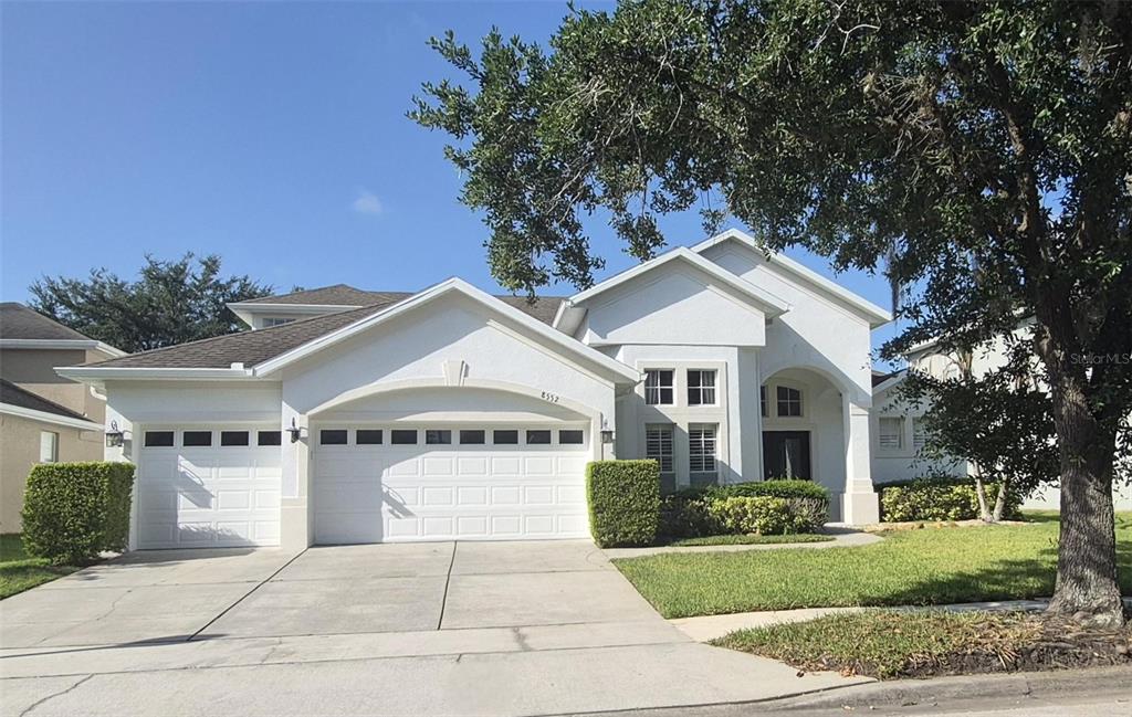 A single-story house with a white stucco exterior, a three-car garage, and a large tree — 8552 KESWICK POINTE DRIVE, ORLANDO, FL
