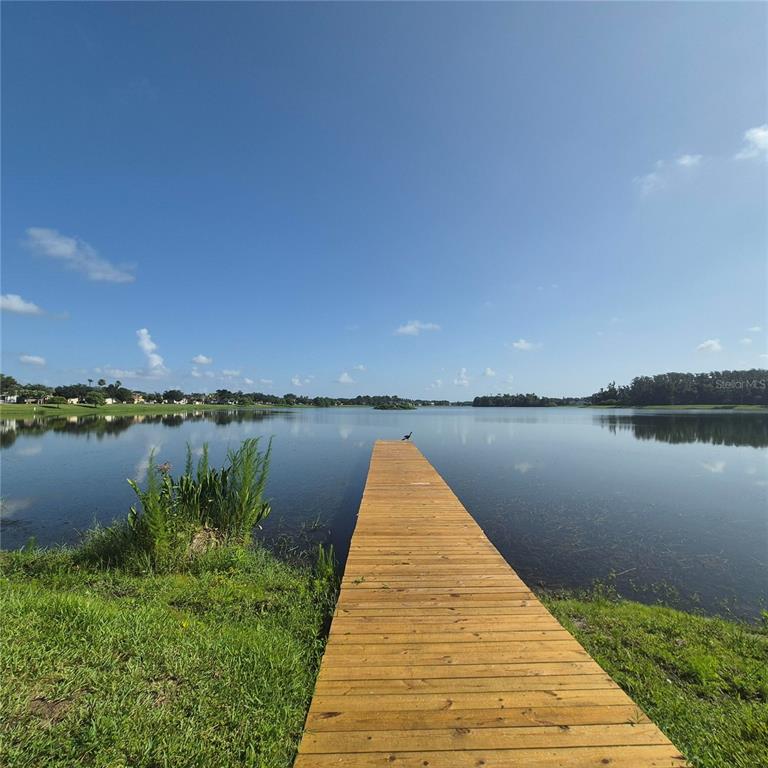 A wooden dock extends into a calm lake under a clear blue sky — 8552 KESWICK POINTE DRIVE, ORLANDO, FL