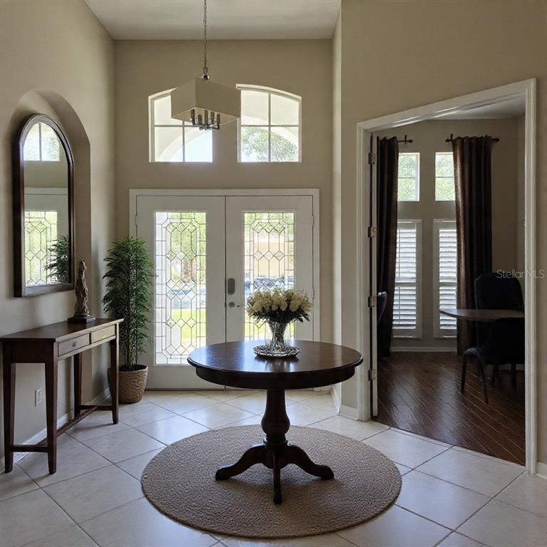 A bright entryway features a round pedestal table, a console table, and double glass doors — 8552 KESWICK POINTE DRIVE, ORLANDO, FL