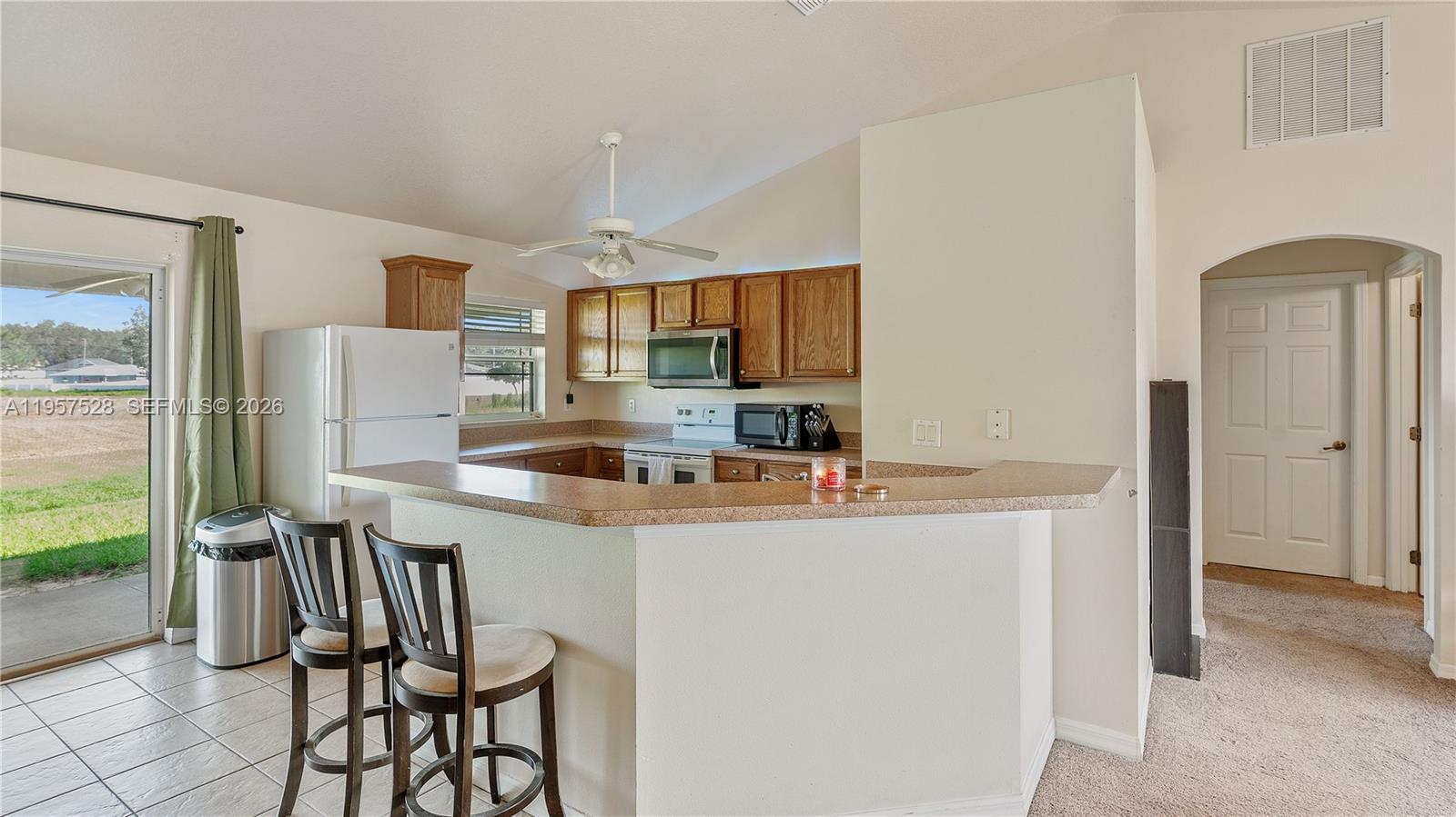 A kitchen features wood cabinets, a breakfast bar, and a sliding glass door to outside — 87 Dogwood Drive Circle, Ocala FL 34472, OCALA, FL