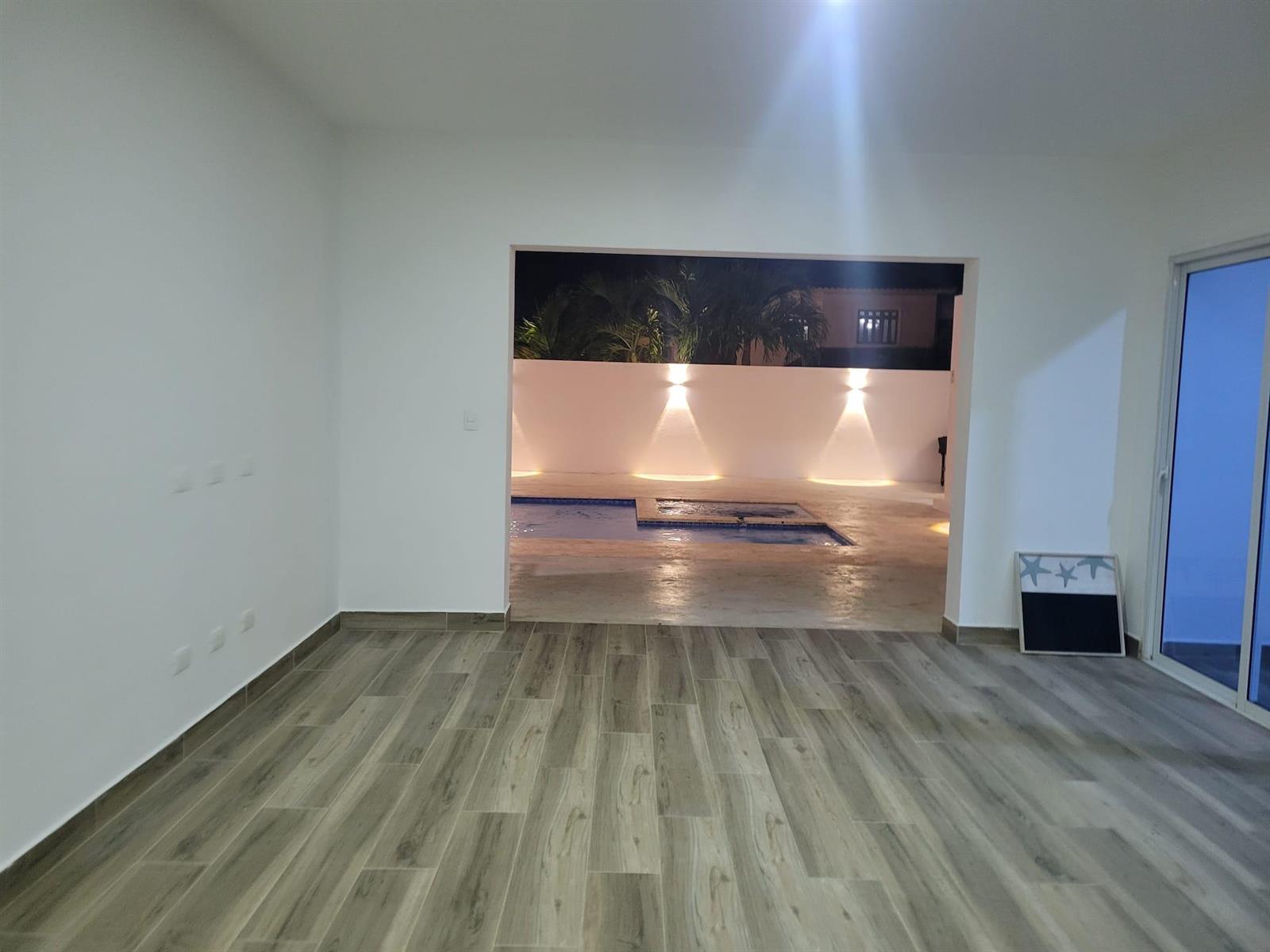 An empty room with wood-look tile flooring opens to a patio with a swimming pool — 0 Residencial Coralina # 3, FL