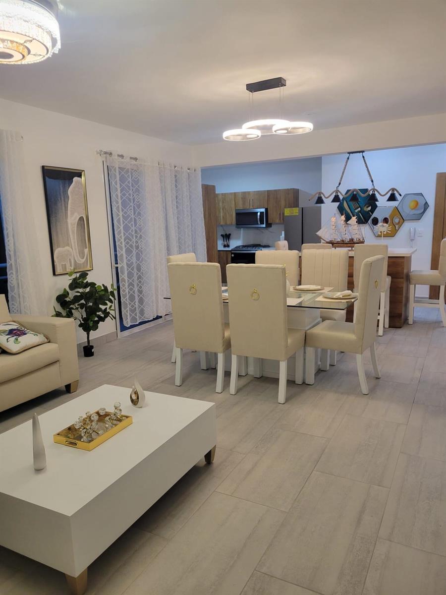 A dining area with a glass table and six chairs sits beside a modern kitchen — 0 Residencial Coralina # 3, FL