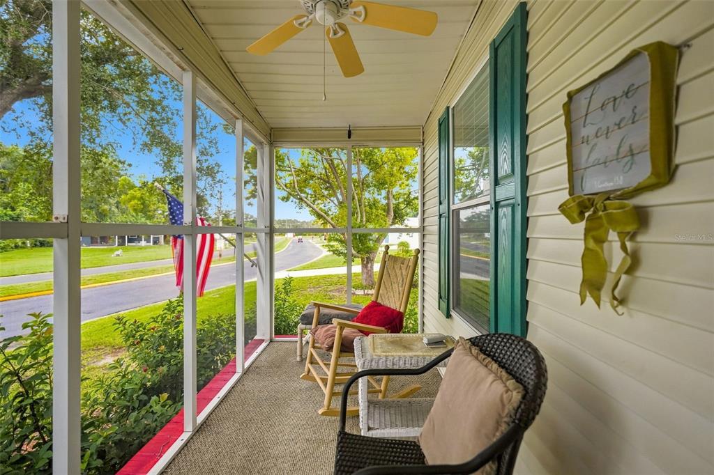 A screened-in porch features a ceiling fan, two chairs, and a decorative wall sign — 5072 BUCCANEER BOULEVARD, SPRING HILL, FL