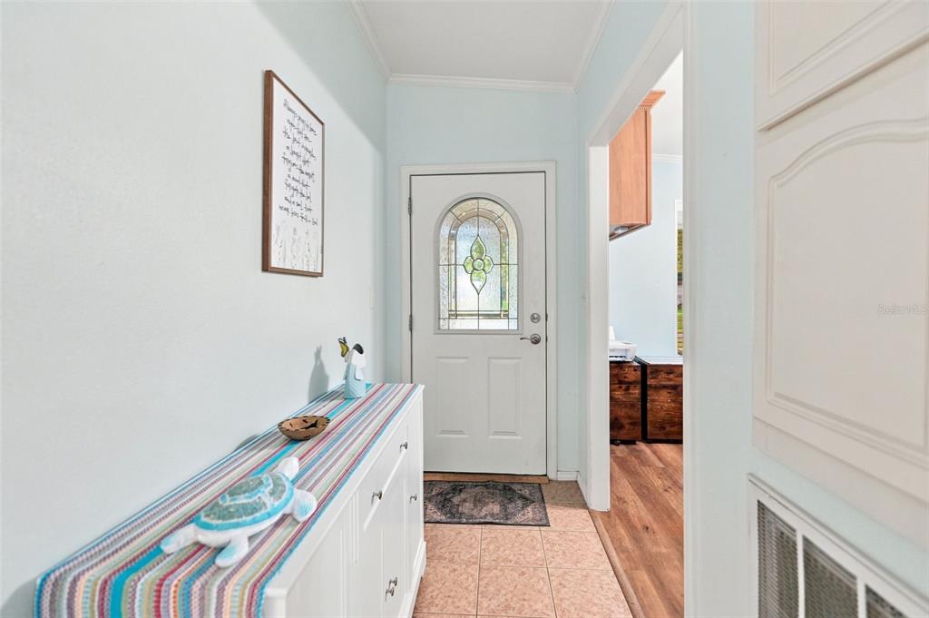 An entryway features a white door with a glass insert, tiled flooring, and a console table — 5072 BUCCANEER BOULEVARD, SPRING HILL, FL