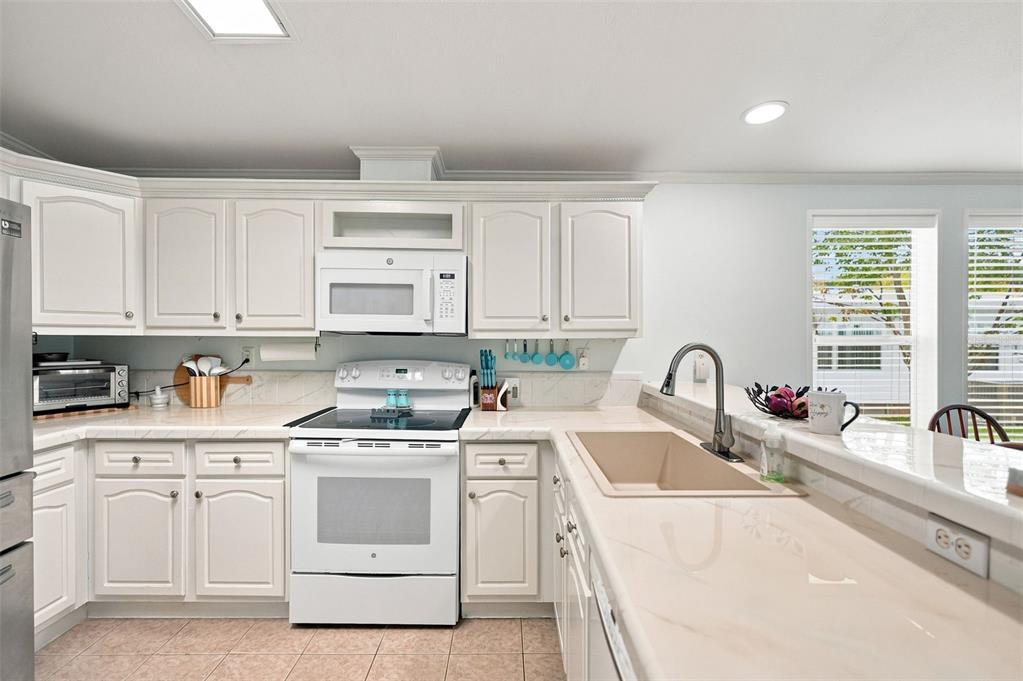 A kitchen with white cabinets, a white stove, and a light-colored countertop with a sink — 5072 BUCCANEER BOULEVARD, SPRING HILL, FL