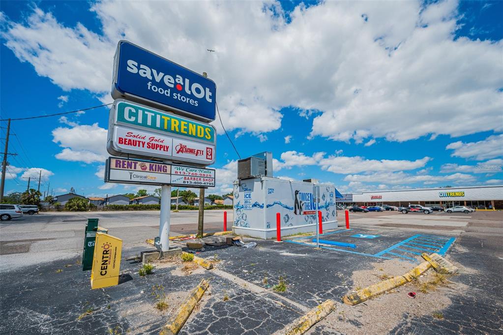A parking lot features a tall shopping center sign and a standalone ice vending machine — 7430 PALM RIVER ROAD, TAMPA, FL