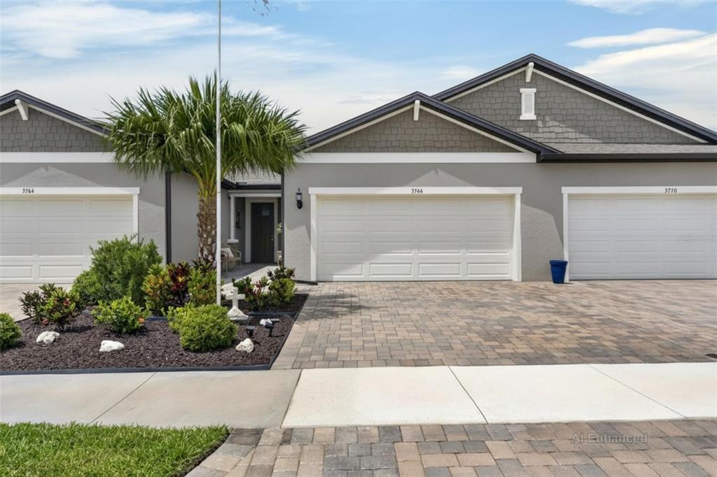 A view of the exterior of three attached single-story homes with gray siding and garages — 3766 LAUGHING DOVE AVENUE, SUN CITY CENTER, FL