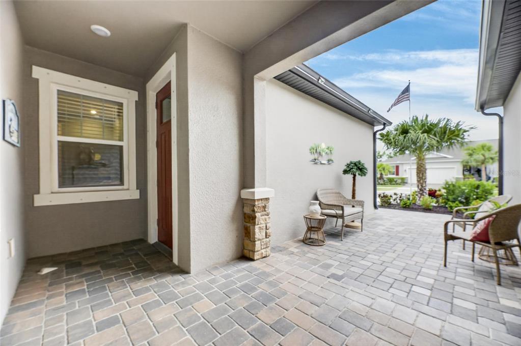 A covered patio with stone-accented columns, paver flooring, and outdoor seating furniture — 3766 LAUGHING DOVE AVENUE, SUN CITY CENTER, FL