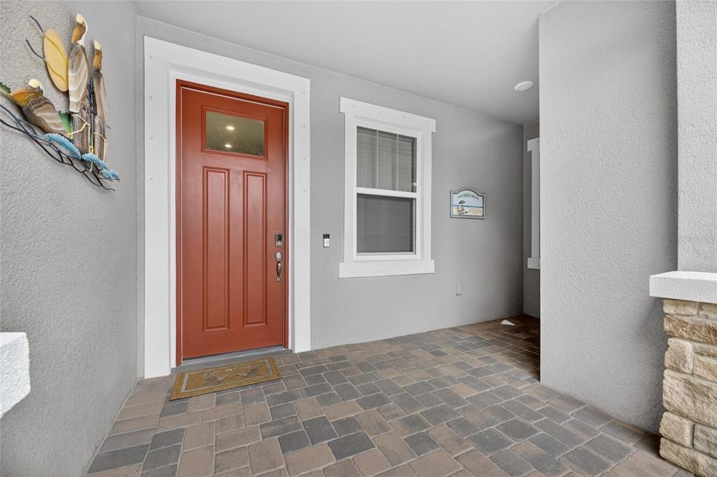 A covered front porch features a red door, a window, and stone pillar accents — 3766 LAUGHING DOVE AVENUE, SUN CITY CENTER, FL