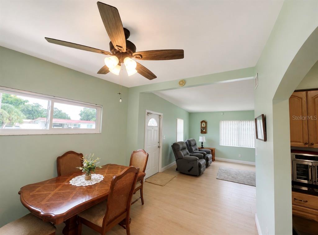 A dining area with a wooden table and ceiling fan opens into a living room — 7812 N GOMEZ AVENUE, TAMPA, FL