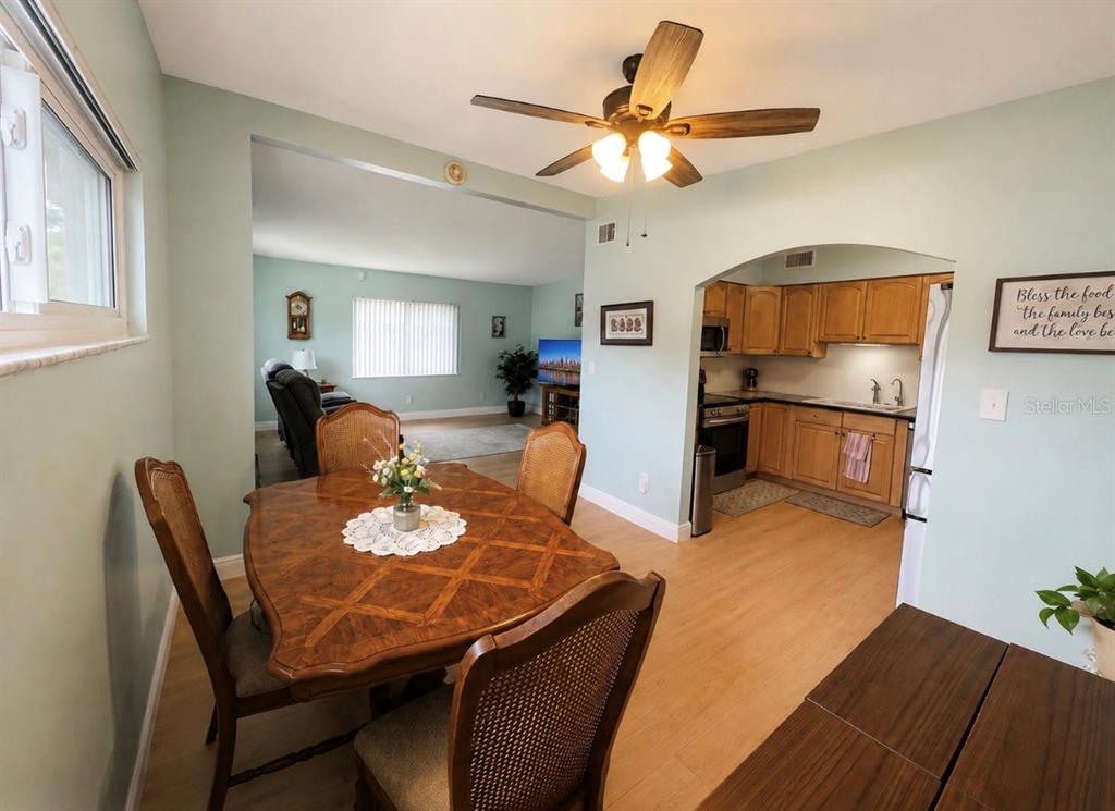 A dining area with a wooden table and chairs opens into a kitchen and living room — 7812 N GOMEZ AVENUE, TAMPA, FL