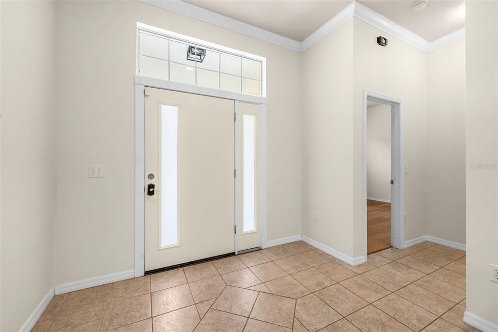 An entryway with tile flooring, a white front door with sidelights, and a transom window — 2501 NW 91ST DRIVE, GAINESVILLE, FL