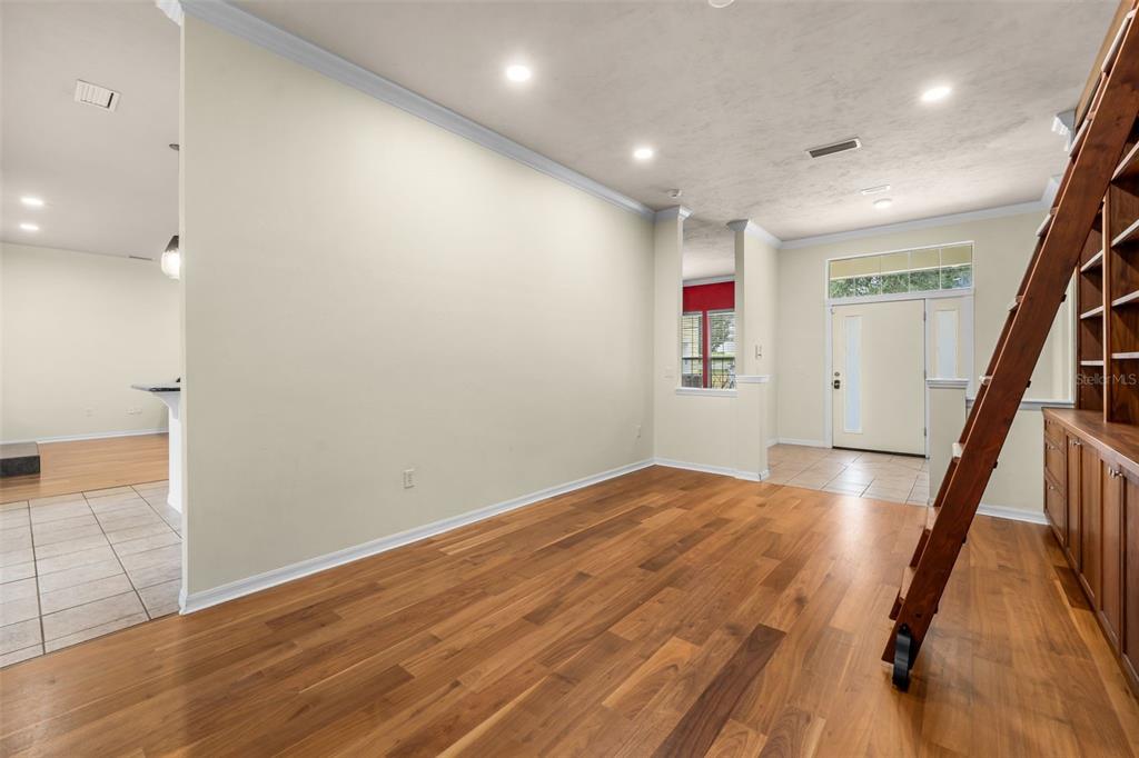 A living room features hardwood floors, a built-in bookshelf with a ladder, and an entryway — 2501 NW 91ST DRIVE, GAINESVILLE, FL